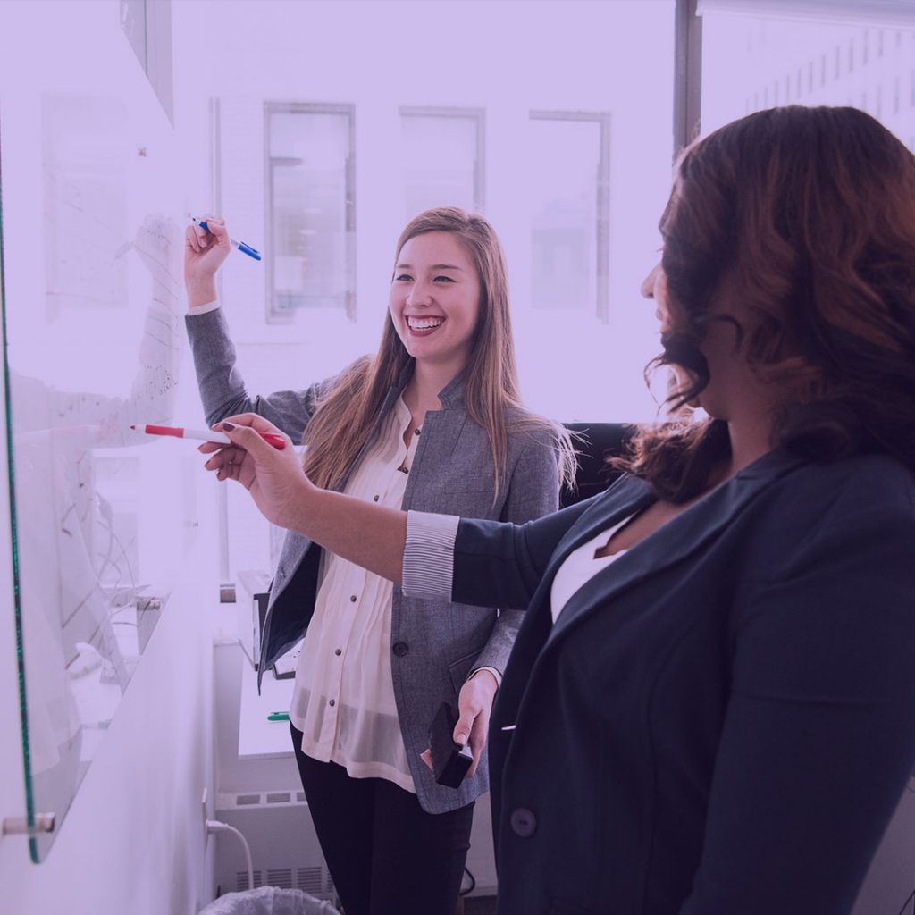 Saleswomen smiling at whiteboard